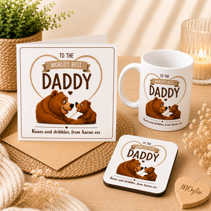 Greeting card, mug, and coaster set with bear design and text 'To the world's best daddy' on a wooden surface.