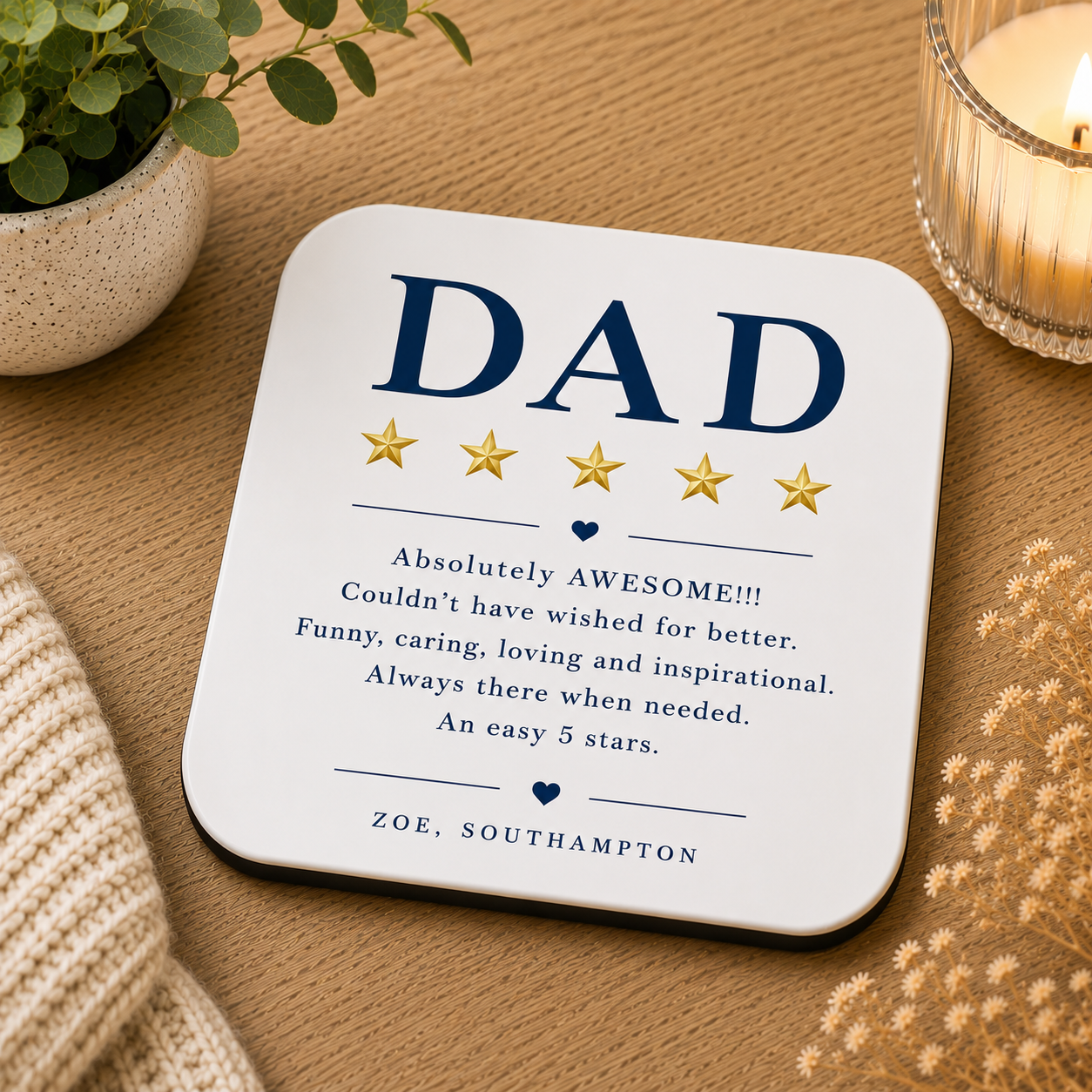 Coaster with 'DAD' and five-star rating on a wooden surface with a plant and candle.