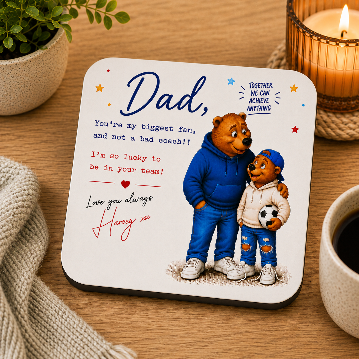 Coaster with cartoon bears and heartfelt message on a wooden surface with a candle and plant.