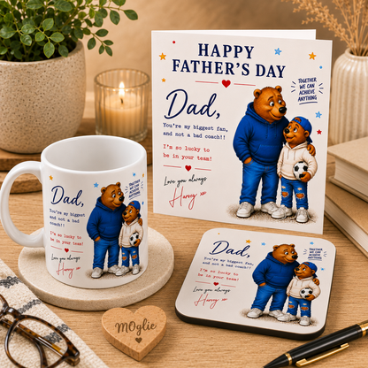 Father's Day card with bear illustration, mug, and coaster on a wooden surface.