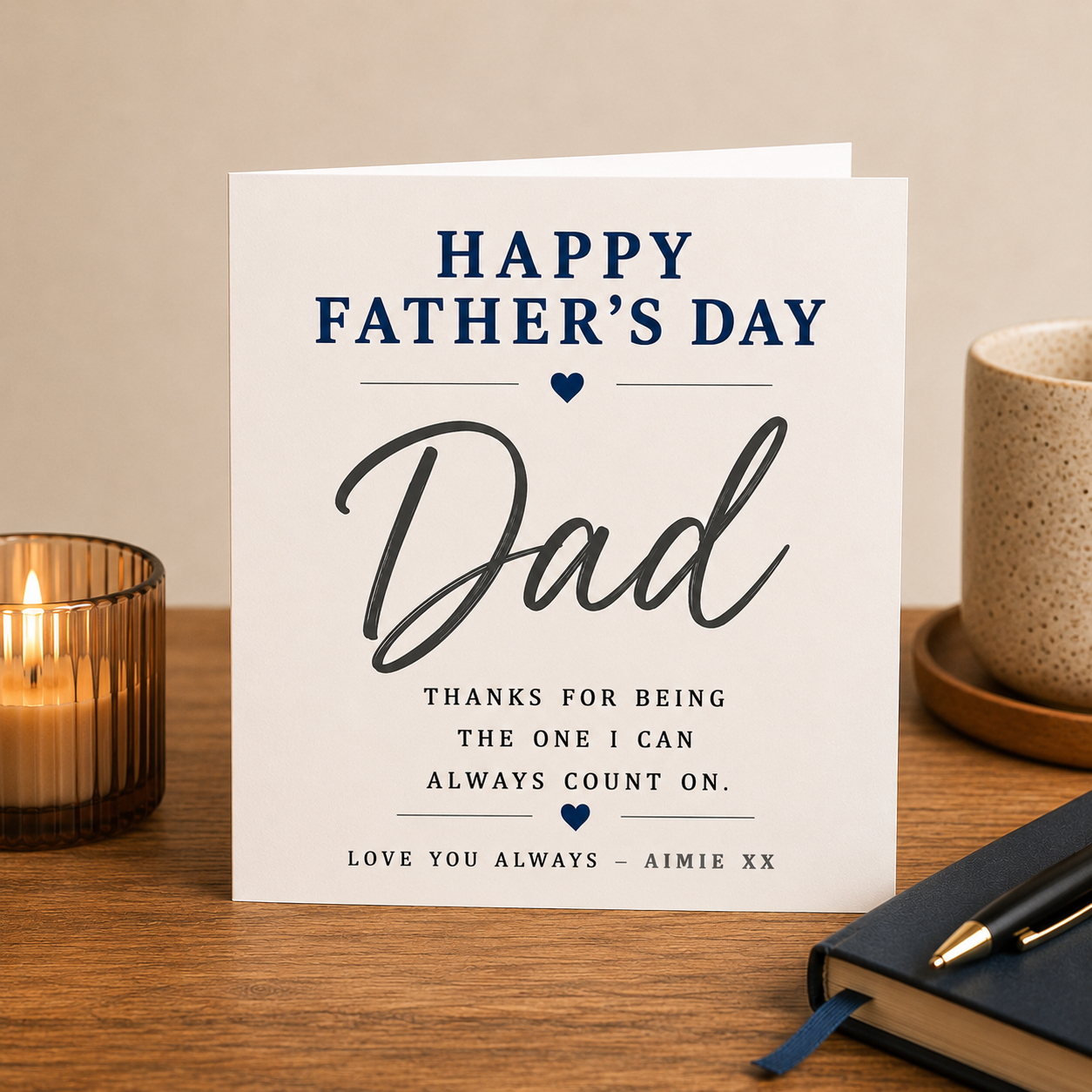 Father's Day card on a wooden surface with a candle and notebook.