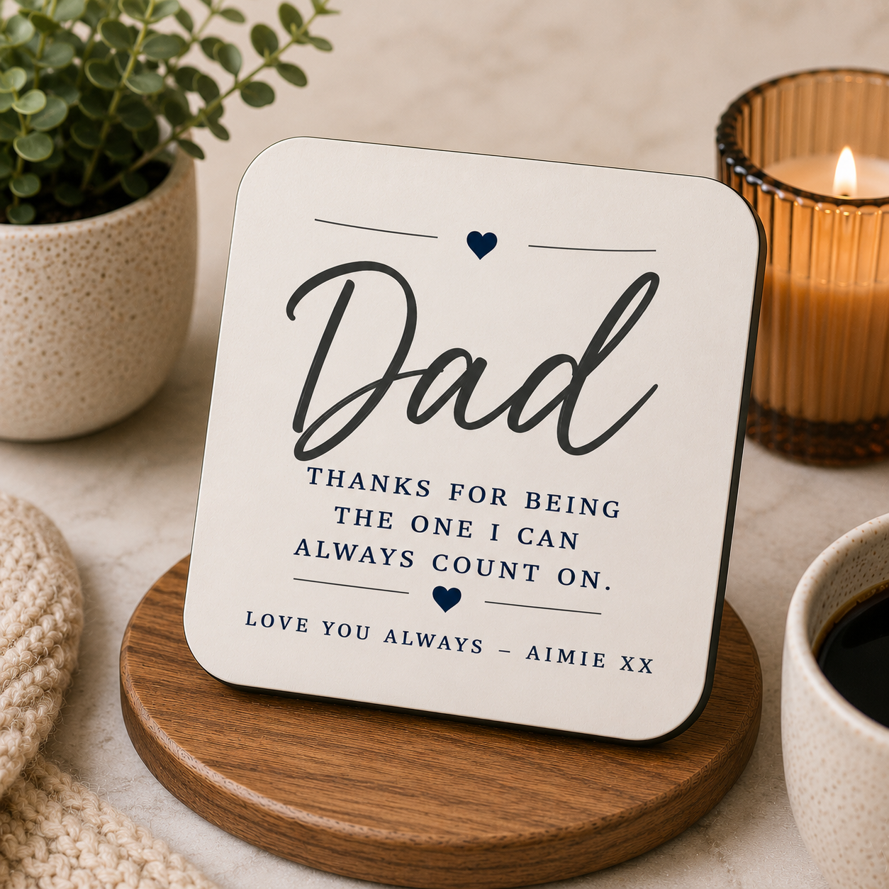 Coaster with a message for Dad on a wooden coaster with a candle and plant in the background.